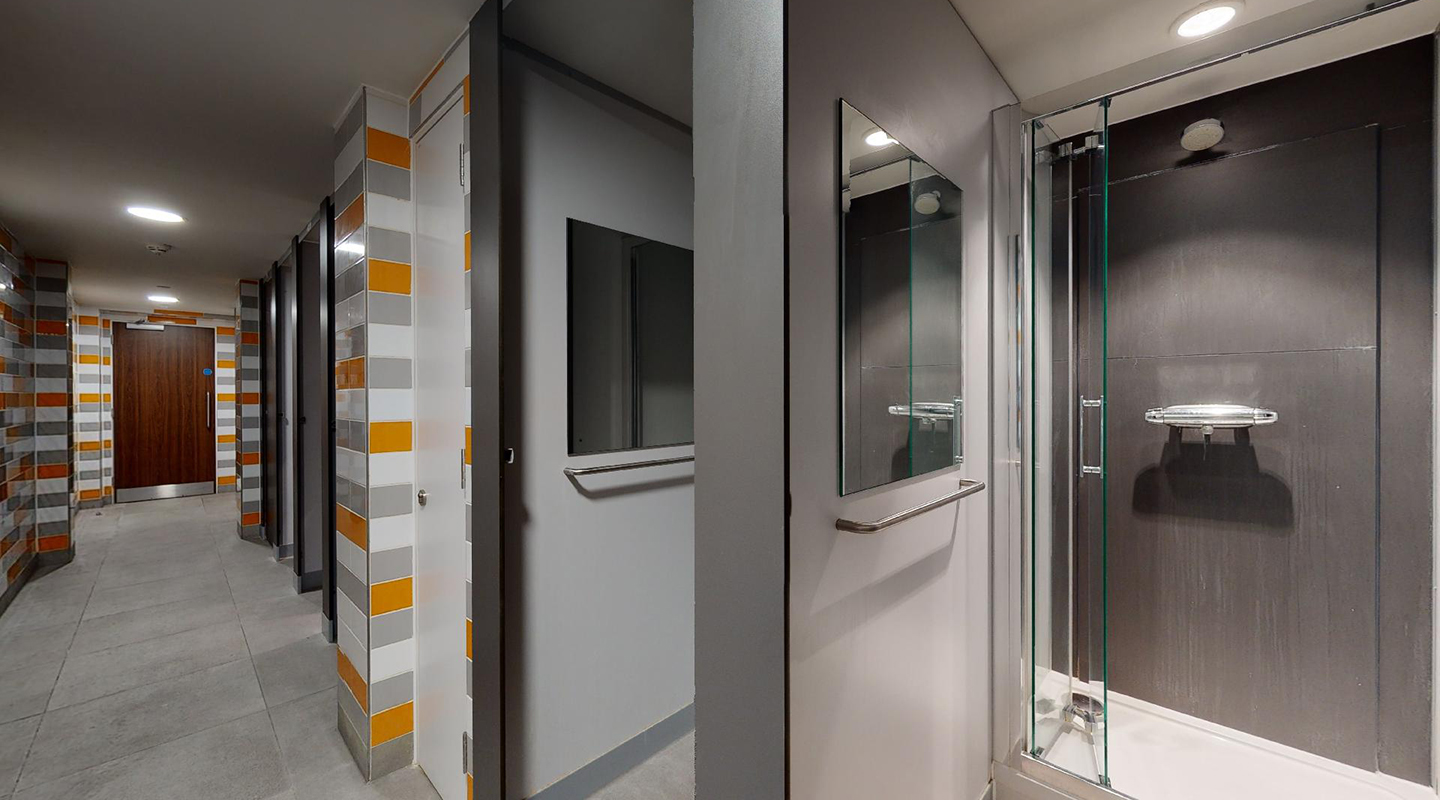 Shared bathroom with multiple shower cubical booths.