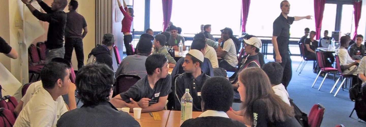 Secondary school-age students taking part in a group activity around a table.