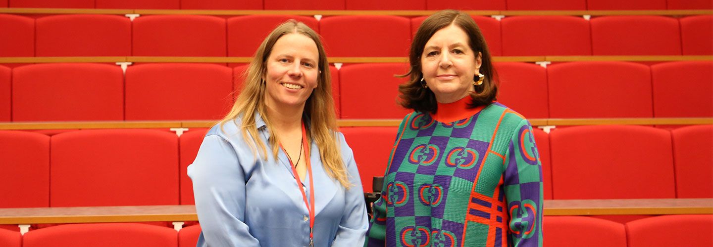 Prof Mel Bunce and journalist Dorothy Byrne stand smile to the camera. They are standing in front of rows of red seats