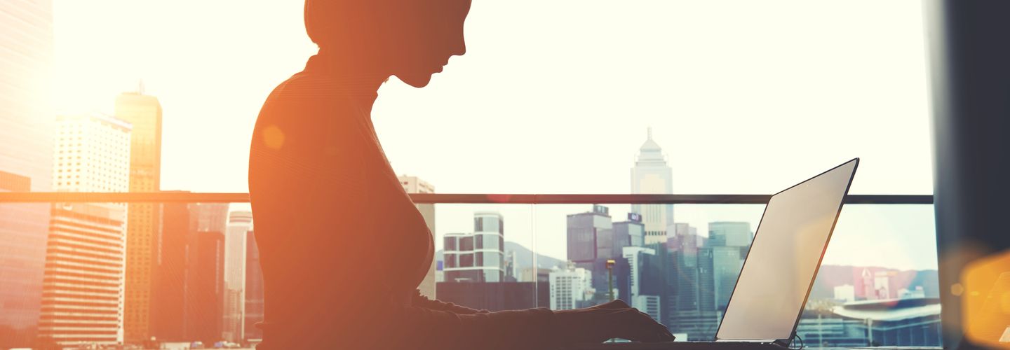 A silhouette of a woman working on a laptop 