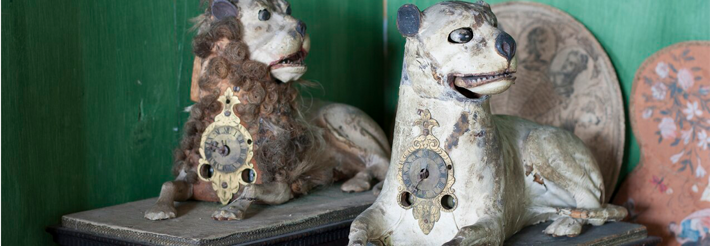 A porcelain lion and a porcelain dog - each with antique clocks embedded in them