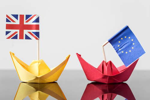 Paper boats with a UK flag and broken EU flag