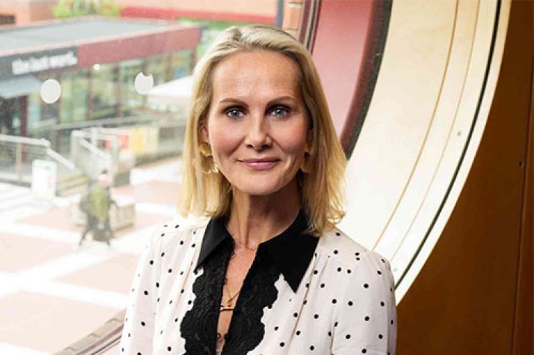 Headshot of Honorary Professor Rebecca Sinclair. She wears a smart black-and-white polka dot shirt and smiles to camera. She stands in front of a window