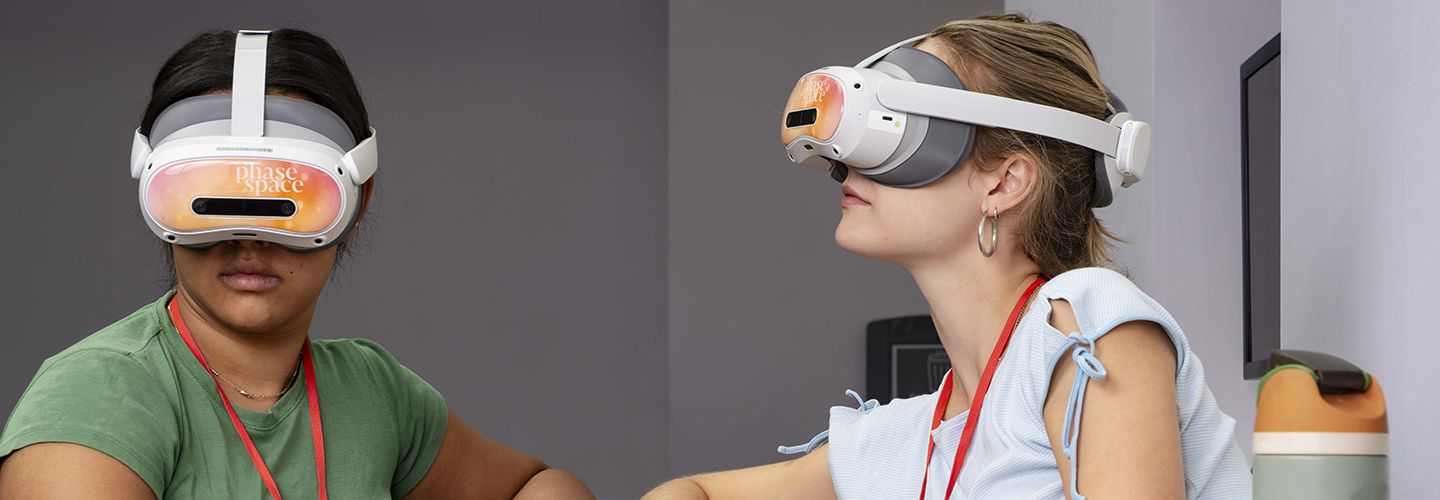 Two individuals wear virtual reality headsets, one looking forward while the other gazes upward.