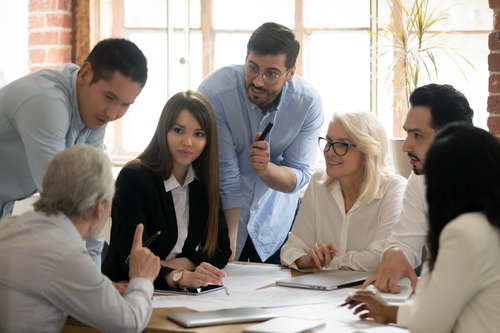 Smiling men and women discussing around a table