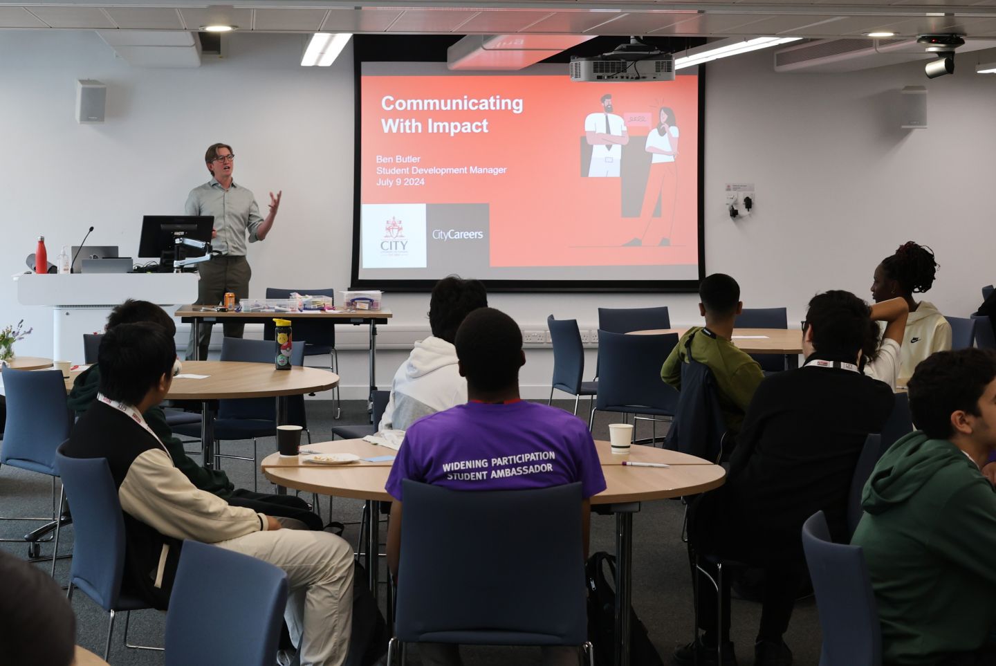 A man delivers a presentation on communication to a room of pupils