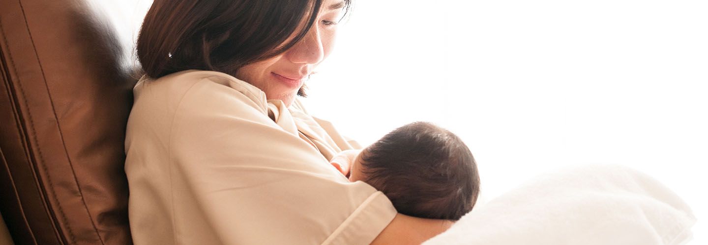 A new mother looks down at her baby who is breastfeeding.