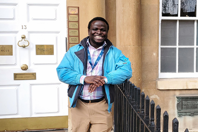 Samson smiles while standing in front of an old building