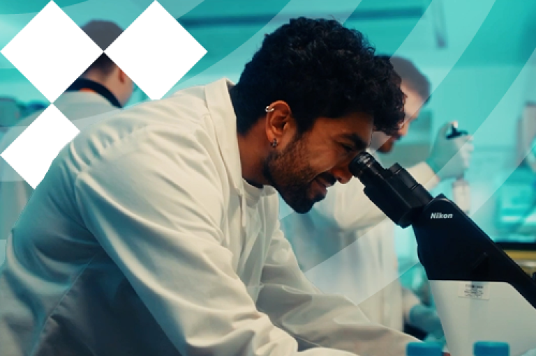 A man in a lab coat examines a microscope, focused on his research in a laboratory setting.