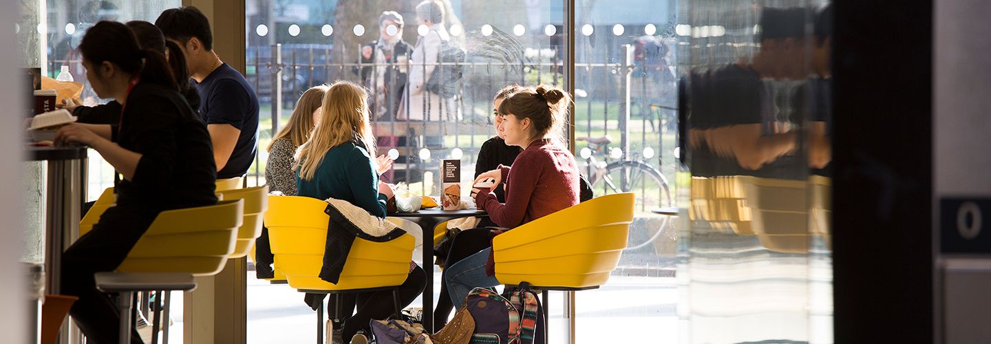 Students sitting in yellow chairs inside the university coffee shop