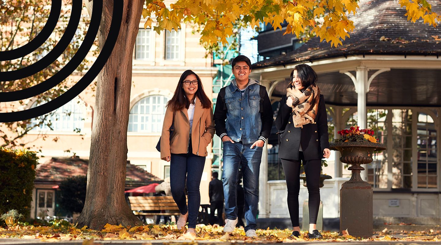 Three students walking outside the bandstand in the Northampton Square