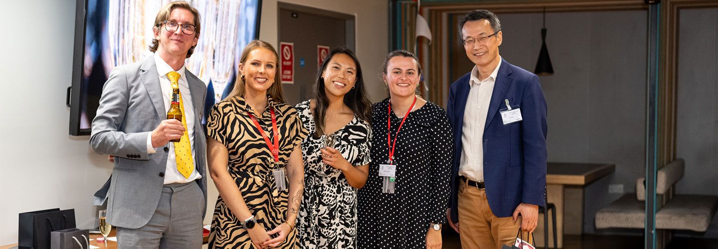 Picture of City staff members smiling at the camera at the City Professional Mentoring Scheme Awards. Xenia and Meghan stand at the centre, both wearing patterned dresses.