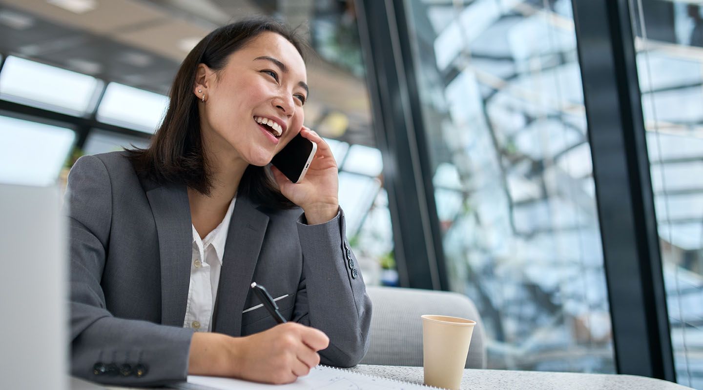 Lady in a communal area smiling and talking on the phone